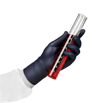 A person's arm in PPE with a black nitrile glove holding a testube with red liquid.